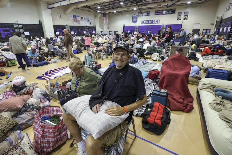 A man smiles at the camera from a crowded school gym.